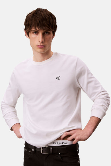 T-shirt blanc à manches longues de Calvin Klein, porté avec un jean noir et un caleçon blanc.