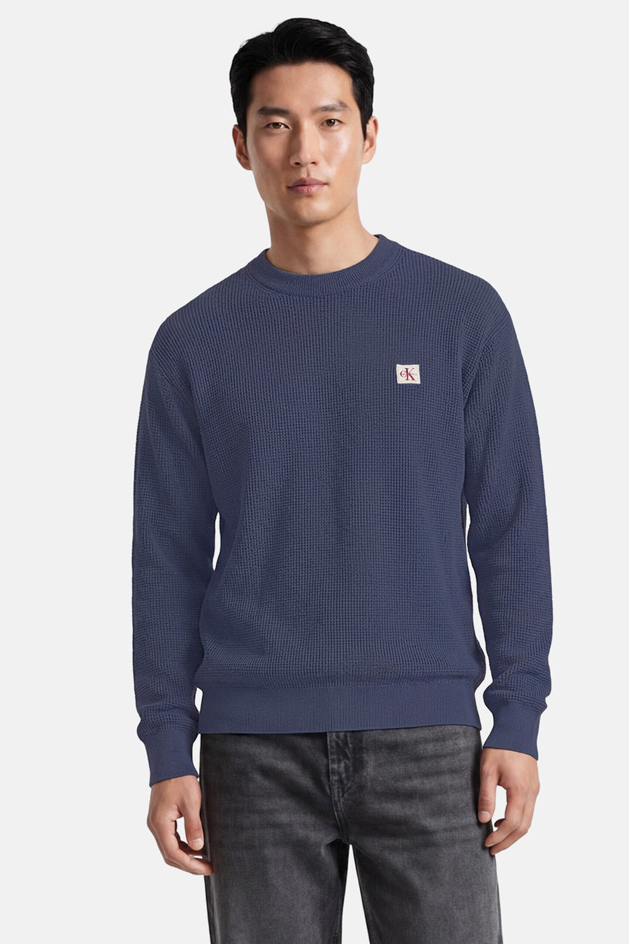 Blauwe ronde hals trui van Calvin Klein met textuur, klein logo op borst, front view, model draagt donkere jeans