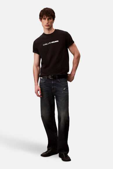 T-shirt noir à manches courtes de Calvin Klein, porté avec des jeans bleu marine et des chaussures noires.