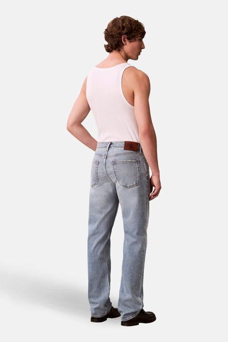 Jeans coupe droite bleu clair denim de Calvin Klein, vue de dos, combinée avec une chemise blanche et des chaussures noires.