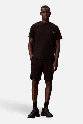 Short noir de Calvin Klein, porté avec un T-shirt noir, des chaussettes noires et des baskets noires.
