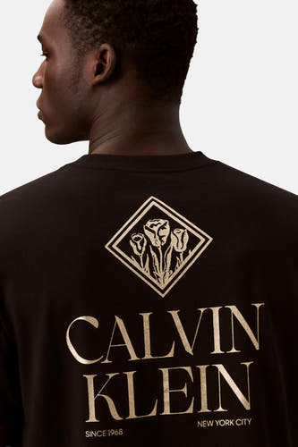 Zwart T-shirt met korte mouwen van Calvin Klein, met gouden opdruk van bloemen in een ruitvorm op de rug.