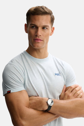 Lichtblauwe korte mouwen T-shirt van SUPERDRY met klein logo op borst, model met gekruiste armen en horloge, vooraanzicht