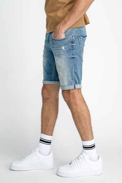 Jean court bleu de Petrol Industries, avec un look retroussé et porté avec des chaussettes blanches et des baskets.