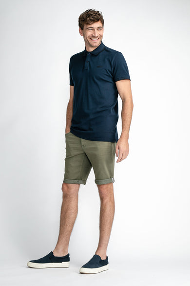 Short en jean vert avec jambes retroussées de Petrol Industries®, porté avec un polo bleu foncé et des baskets, vue de face