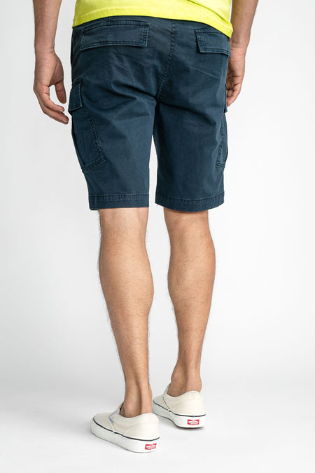 Short cargo bleu de Petrol Industries®, dos avec poches, porté avec un t-shirt jaune et des baskets blanches