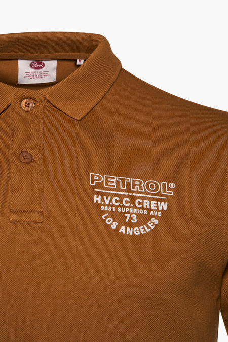 Polo cognac de Petrol Industries® avec logo brodé blanc sur la poitrine, texture côtelée et fermeture à boutons, gros plan sur l'avant