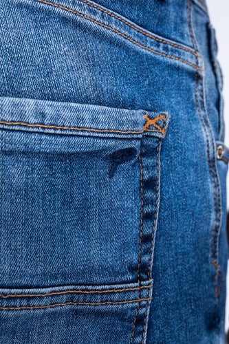 Close-up van blauwe jeansstof met zak en bruine stiksels.
