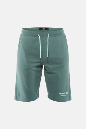 Shorts verts de Petrol Industries, avec cordon blanc et un logo de la marque sur la jambe, portés avec un t-shirt gris et des baskets.