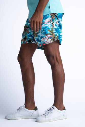 Short de bain bleu de Petrol Industries, avec imprimé tropical de palmiers et surfeurs, et baskets blanches.