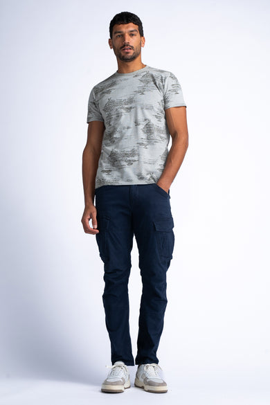 T-shirt vert de Petrol Industries, avec des manches courtes et un motif all-over, associé à des pantalons cargo bleu marine et des baskets.