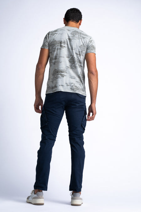T-shirt vert de Petrol Industries, avec des manches courtes et un léger motif sur le dos, associé à un pantalon bleu marine et des baskets blanches.