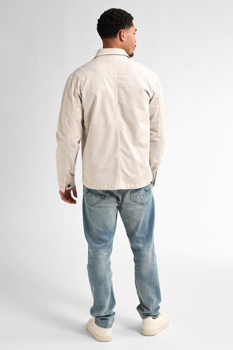 Man van achteren, beige jas, blauwe jeans, crèmekleurige schoenen.
