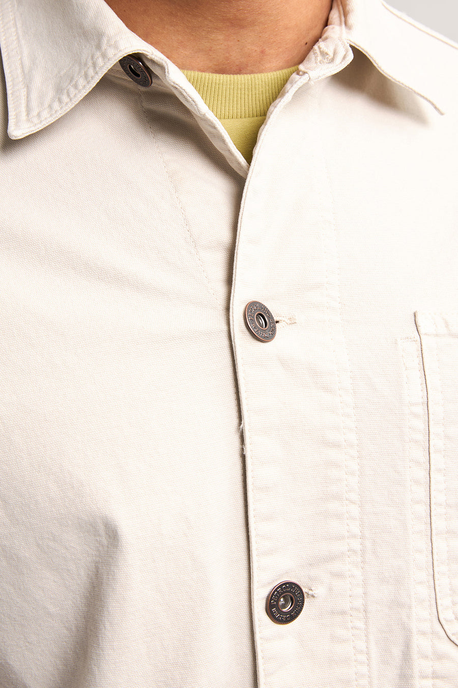 Beige overhemd met bruine knopen.
