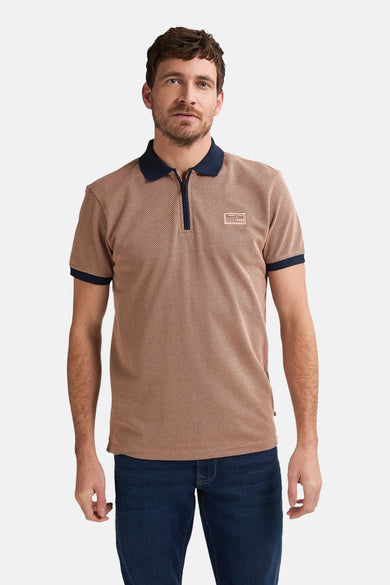 Man in een bruin gemêleerd poloshirt met blauwe accenten en jeans.
