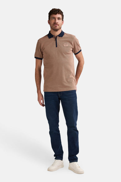 Man in bruine polo en donkerblauwe jeans.