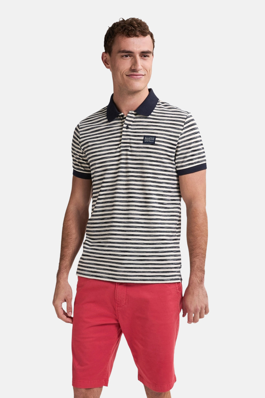 Man met gestreepte polo en rode korte broek.