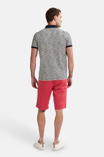 Een man in een gestreept poloshirt en rode korte broek, van achteren gezien.