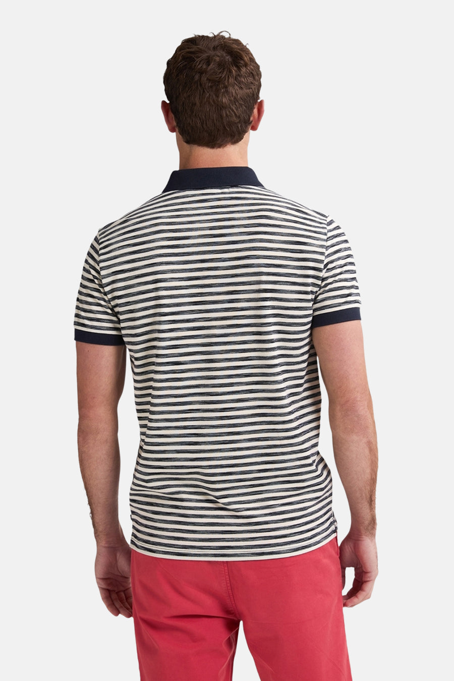 Achterkant van een man in gestreept poloshirt en rode short.