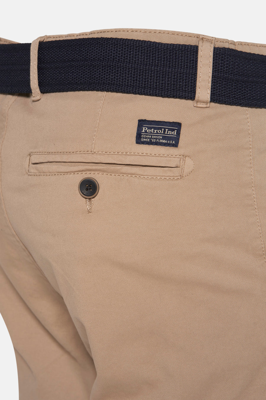 Beige katoenen broek met donkerblauwe riem.