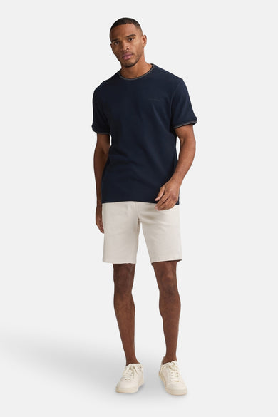 Beige court de Petrol Industries®, associé à un T-shirt bleu marine et des baskets blanches.