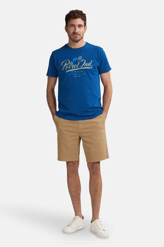 Beige court de Petrol Industries, porté avec un t-shirt bleu et des baskets blanches.