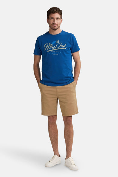 Beige court de Petrol Industries, porté avec un t-shirt bleu et des baskets blanches.