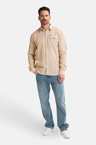 Chemise beige à longues manches de Petrol Industries, avec poche poitrine et portée avec des jeans bleus et des baskets blanches.
