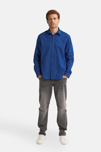 Chemise bleue à manches longues de Petrol Industries, portée avec des jeans gris et des chaussures blanches.
