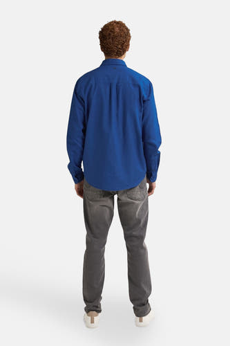 Blauw overhemd met lange mouwen van Petrol Industries®, gezien vanaf de achterkant, gecombineerd met een grijze jeans en witte sneakers.