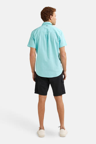 Chemise turquoise à manches courtes de Petrol Industries®, dos, associée à des short noirs et des chaussures crème.