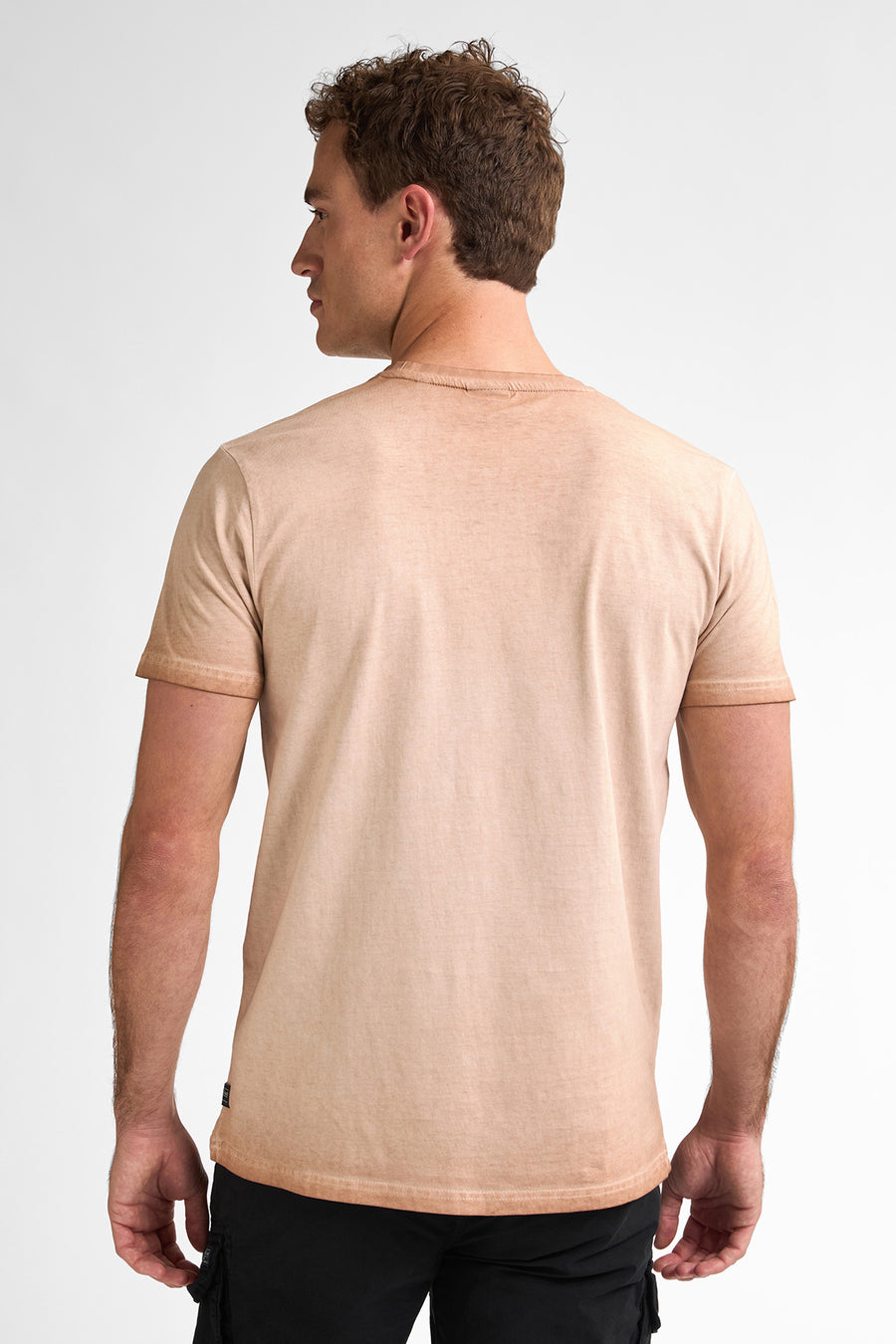 Achterkant van een man in een beige T-shirt.