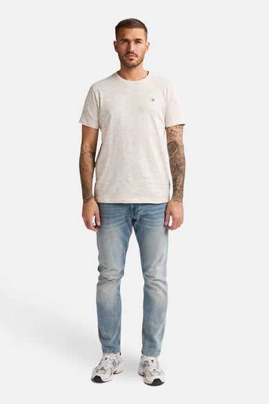 T-shirt écru à manches courtes de Petrol Industries, avec un effet tacheté, porté avec un jean et des baskets.