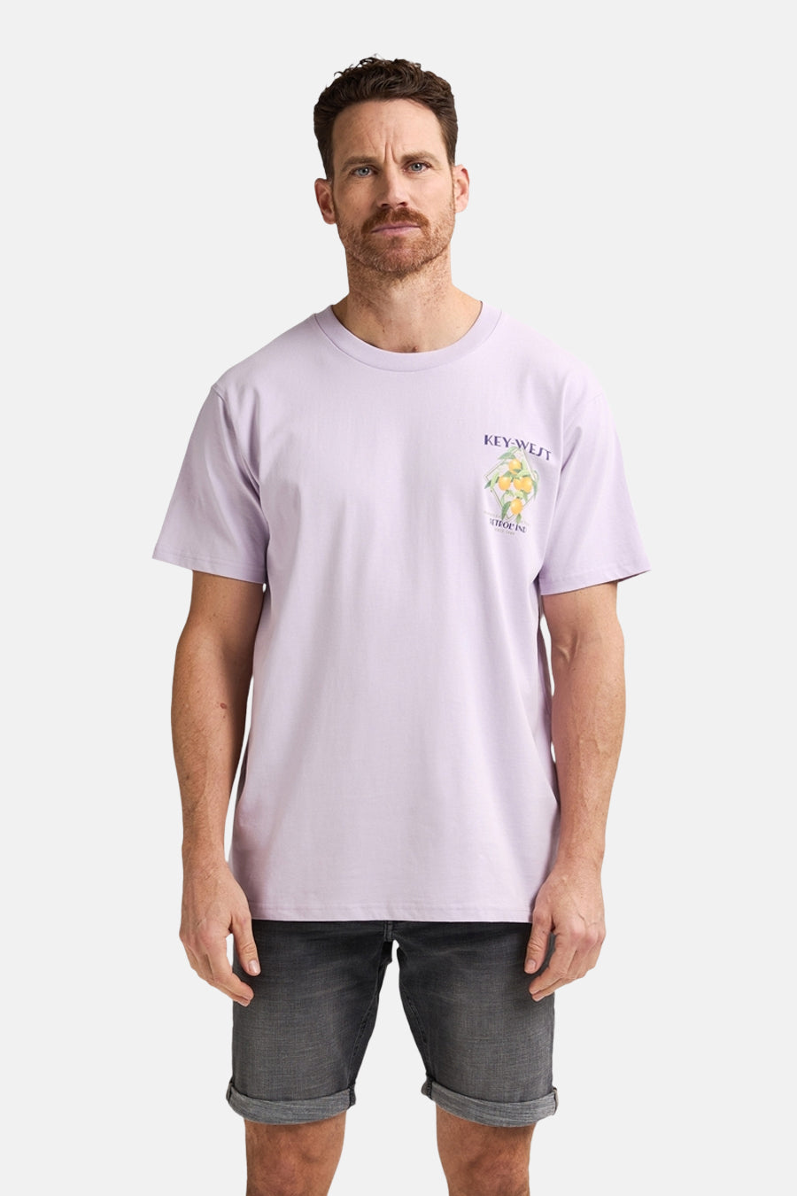 Man draagt lila t-shirt met opdruk en grijze denim shorts.