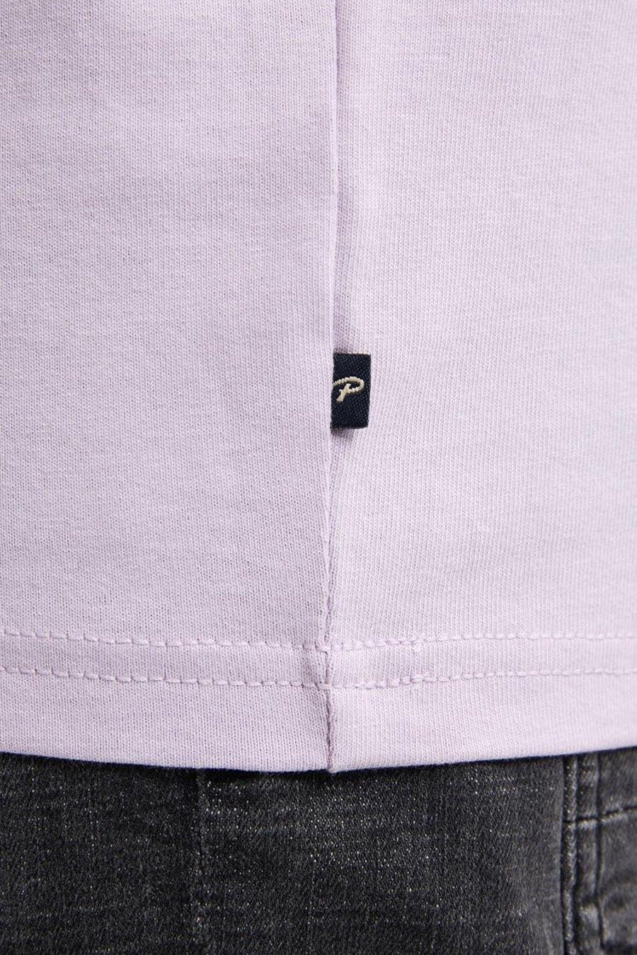 Lila T-shirt met logo en zwarte jeans.
