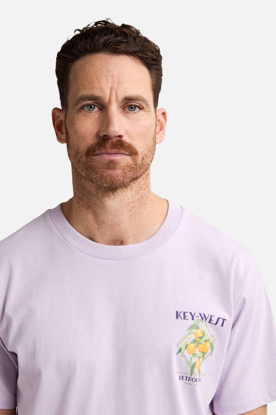 Een man draagt een lila T-shirt met Key-West print.