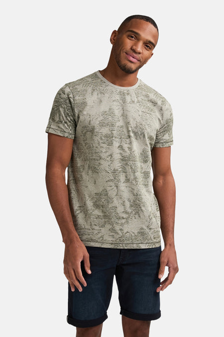 T-shirt vert avec manches courtes de Petrol Industries®, avec une impression de feuilles sur toute la surface, associé à des shorts en denim bleu marine.