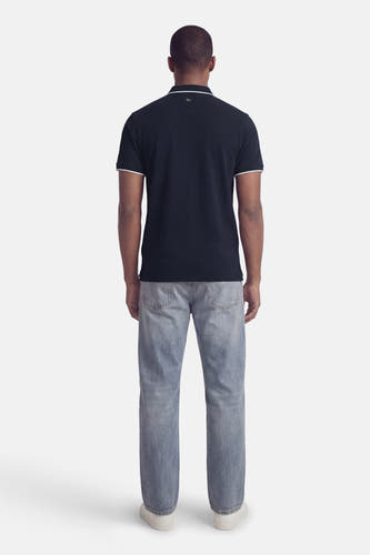 Blauwe polo met korte mouwen van Petrol Industries®, met witte accenten op kraag en mouwen, gecombineerd met jeans en witte schoenen, achterkant.