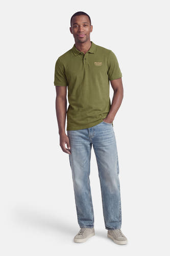 Groene polo met korte mouwen van Petrol Industries®, gedragen met jeans en grijze sneakers.
