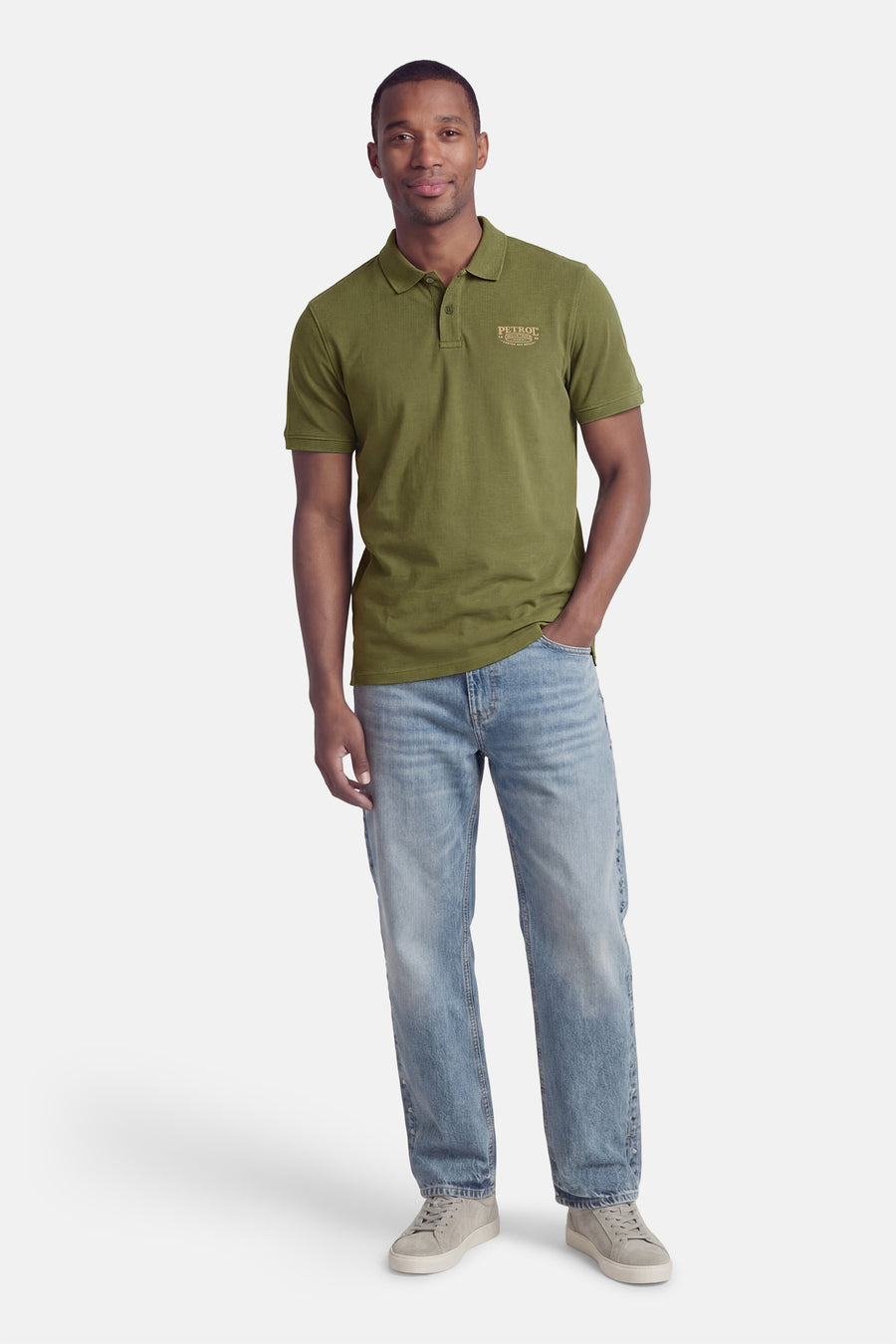 Groene polo met korte mouwen van Petrol Industries®, gedragen met jeans en grijze sneakers.
