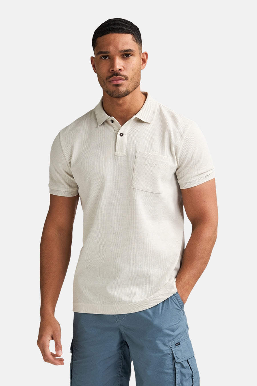 Polo écru de Petrol Industries®, vue de dos, combinée avec un short cargo bleu et des baskets blanches.