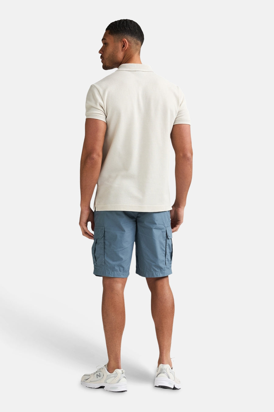 Ecru polo van Petrol Industries®, gezien van achteren, gecombineerd met blauwe cargoshorts en witte sneakers.