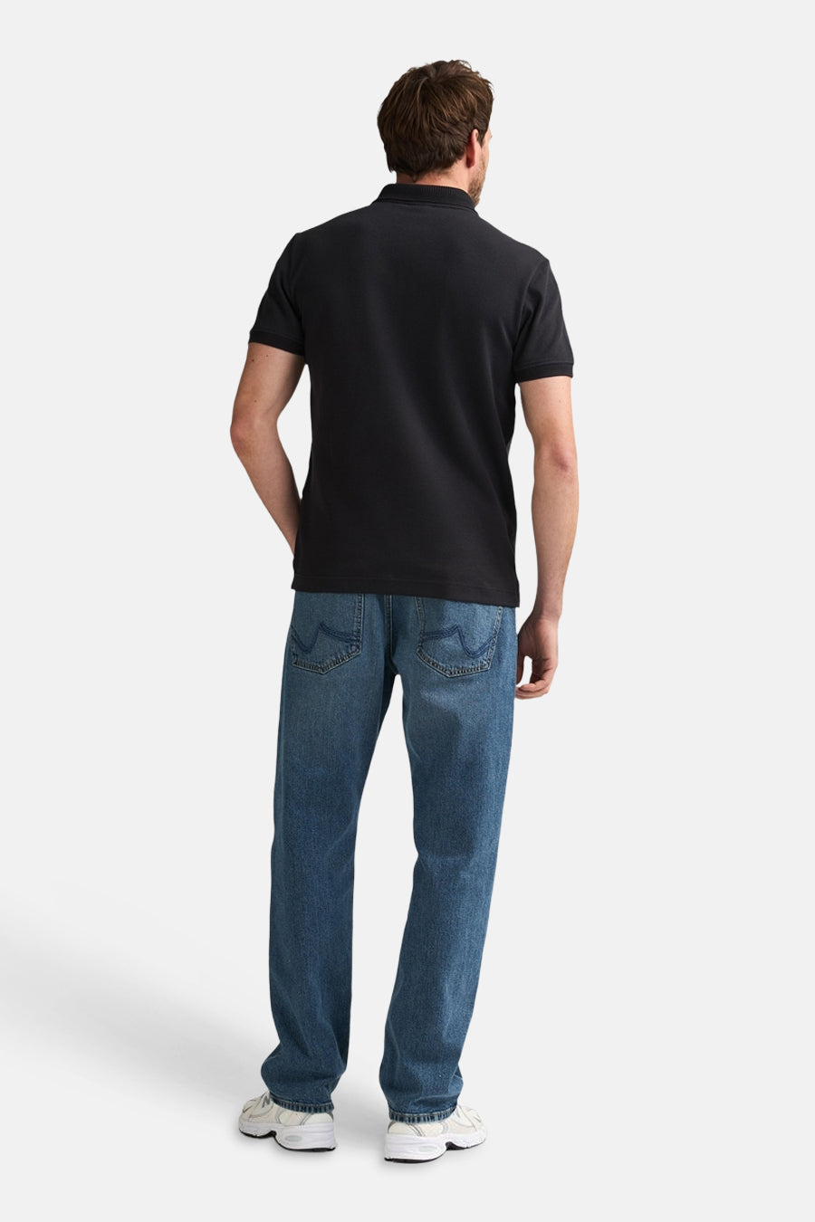 Zwarte polo van Petrol Industries® op de rug gezien, gecombineerd met blauwe jeans en witte sneakers.