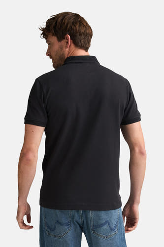 Polo noire de Petrol Industries, vue de dos, à manches courtes et portée avec un jean.
