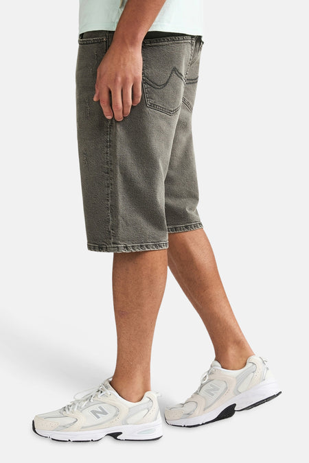 Short en jean gris moyen de Petrol Industries®, en vue de côté, avec effet délavé et baskets blanches.