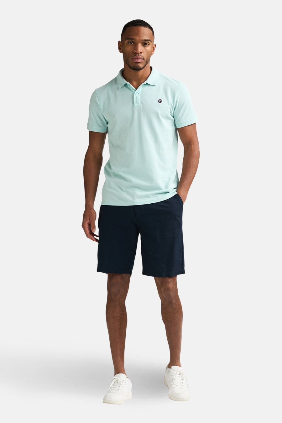 Blauwe short van Petrol Industries, gedragen met een lichtblauwe polo en witte sneakers.
