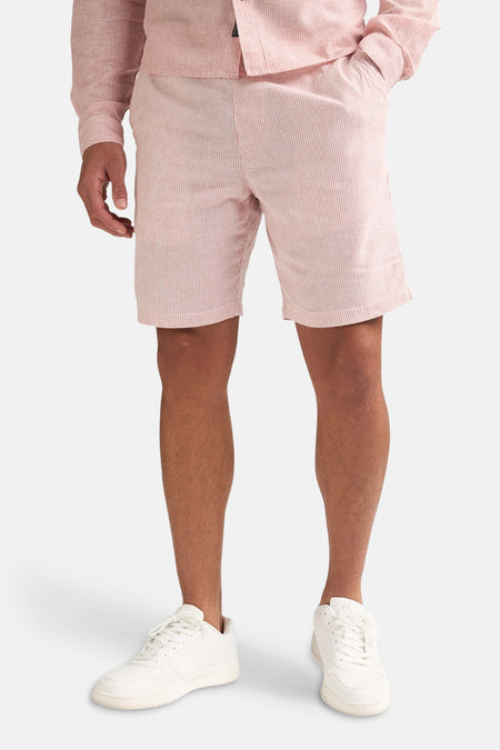Gros plan d'un short rayé rose de Petrol Industries®, avec de fines rayures verticales blanches et une étiquette tissée de la marque.