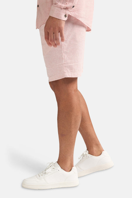 Short rayé rose de Petrol Industries, porté avec une chemise assortie et des baskets blanches.