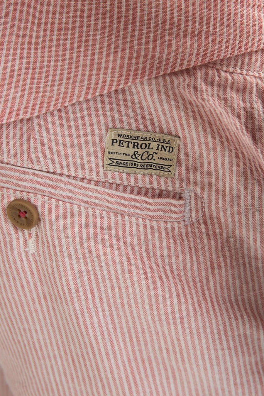 Short rayé rose de Petrol Industries, avec étiquette textile beige et bouton marron.
