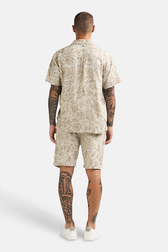 Beige short van Petrol Industries® met paisley-patroon, gecombineerd met een bijpassend overhemd en witte schoenen, van achteren gezien.